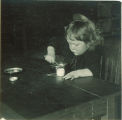 Small child spooning something into a small cup, The University of Iowa, 1920s