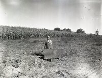 Farmer in overalls holds metal sheet in a field