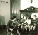 Small boy on piano bench helping a woman play violin, The University of Iowa, January 12, 1938