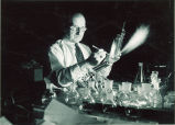 Man blowing glass to create chemistry equipment, The University of Iowa, February 11, 1938