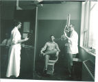 Dental students taking bite wing x-rays for a patient in a clinic, The University of Iowa, September 1954