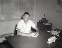 Unidentified man sits at desk holding pen