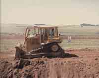 Couple Watching Bulldozer in Field