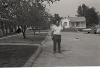 Unidentified Man Stands in Street with Hand Raised