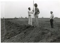 1979   William Baugh, Des Moines County soil conservation aid, holds a measuring tool in a field while two men watch