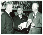 Looking at companion book to Philip D. Sang exhibition, left to right, Iowa Gov. Leo Hoegh, Philip D. Sang, and Library director Ralph Ellsworth, The University of Iowa, 1956