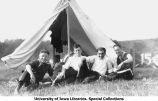 Cadets seated next to tent at Camp Macbride, The University of Iowa, 1914