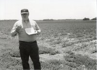 Unidentified man in glasses and hat in field speaks to unseen audience