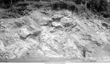 Man standing near oblique bedding at Sugar Creek lime quarries, Sugar Creek, Iowa, late 1890s or early 1900s