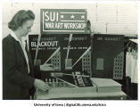 Art instructor Alice Davis examining posters at war art workshop, The University of Iowa, ca. 1942