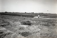 Man Stands by TOT Pipe in Field