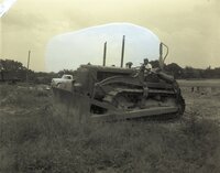Man drives International bulldozer with Bucyrus Erie bulldozer blade in a grassy field
