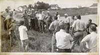 Unidentified Man with Glasses Talks to Group Standing Beside Farm Pond
