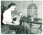 Physics graduate student looking at data from shock and vibration test of satellite instruments, The University of Iowa, 1963