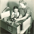 Girl and researcher playing with dollhouse, The University of Iowa, November 11, 1940