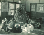 Children sitting around a Christmas tree in a classroom, The University of Iowa, 1920s