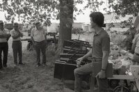 Men stand under tree during a meeting