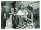 Teacher and students looking at book, The University of Iowa, July 1957