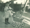 Small child pushing a doll in a baby carriage, The University of Iowa, 1920s