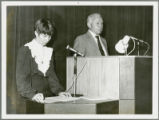 Earl O. Heady at a lectern in Hungary in 1979, with a woman translator on the left.
