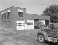 Nelson Trucking Service trucks sit by brick garage