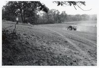 1978 Theresa Beckman walks toward tractor and wagon planting seed