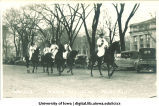 Men with surveying poles on horseback in Mecca Day parade, The University of Iowa, 1920