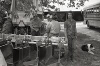 Men stand under tree during a meeting
