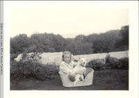 Frindy Burden and Denise, the dog sitting in basket in rock garden