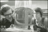 Two researchers studying liquid in a glass cylinder, 1978