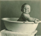 Smiling baby sitting in a wash basin, The University of Iowa, 1920s