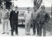 Men stand under tree during a meeting