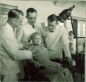 Dental students examining with a small girl, The University of Iowa, 1940s