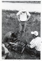 Three men study aerial photos