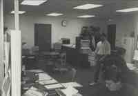 Office photo of man walking and two sitting