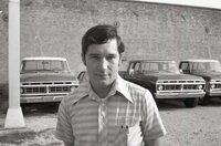 Unidentified man stands in front of trucks