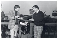 Two men stand by Ford service sign