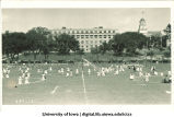 Children dancing and playing games with May poles near the Pentacrest, The University of Iowa, 1920s