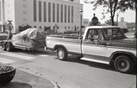 Truck pulling trailer with two smiling men inside
