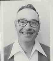 Closeup of Unidentified Commissioner in Glasses and White Shirt with pointed collar.