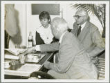 Earl O. Heady pointing at a book while having beverages in Hungary with J. Toth and a woman translator, 1979