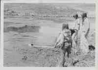 Girls retrieving object from pond