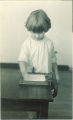 Little girl standing and writing at a table, The University of Iowa, 1920s