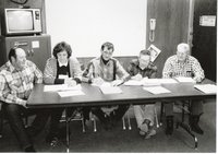 Five unidentified workers sit at table for meeting