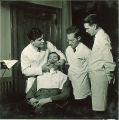 Dental students working with a patient wearing a dental dam, The University of Iowa, 1940s