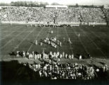 Football players on the field during the Homecoming football game, 1959