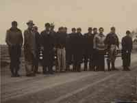 Unidentified gathering of people standing on an unpaved road