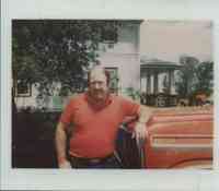 Unidentified Man in Orange Shirt leaning against Orange Truck