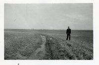 Unidentified Man Walks in Pasture Beside Water Running Down Field