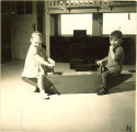 Smiling toddlers on an indoor seesaw, The University of Iowa, January 12, 1938